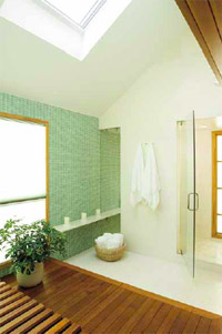 Wood, glass, and stone come together again in the master bathroom in the back of the house on the lower level. Limestone covers the floor and lines the shower chamber, which also features a frameless door and frosted-glass exterior window. The soft green glass-tile accent wall showcases the cedar platform, bench, and soaking tub (not shown); surrounding windows look into an enclosed garden outside. Two skylights let in the light.