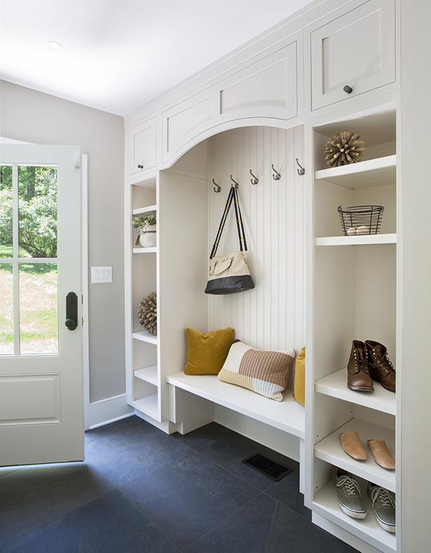 In the new mudroom entry, beadboard, Shaker-style cabinets and slate-like floor tiles suit the
                architecture of the house. Glass panes on the door let natural light into the space.