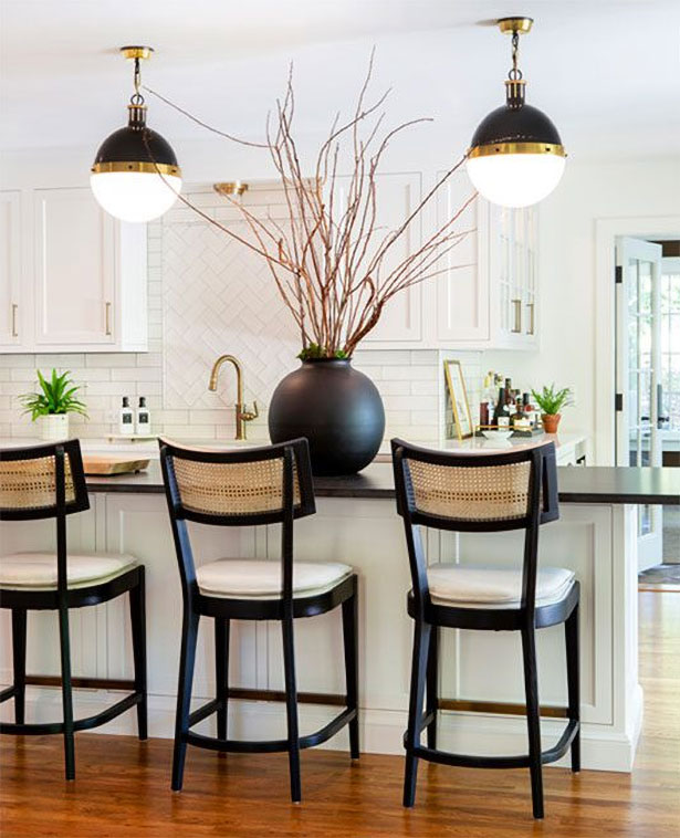 Black accents create a striking contrast to the kitchen’s white foundation.