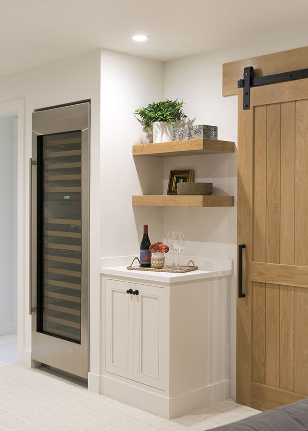 At the bottom of the stairs is a large wine chiller and a cabinet that serves as a bar.